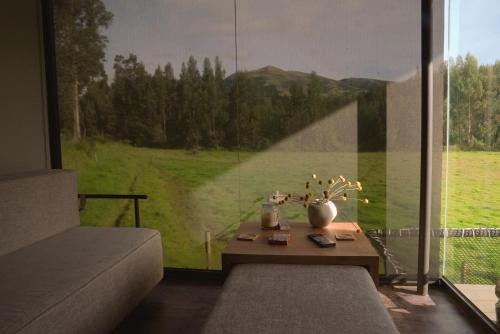 a living room with a table and a large window at Las Cabañas by PMJ in Cayambe