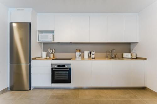 a kitchen with white cabinets and a stainless steel refrigerator at Oceanfront Oasis - Stunning beach view apartment in El Médano
