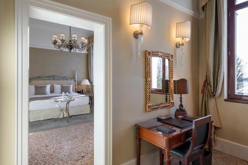 a bedroom with a bed and a desk and a mirror at San Clemente Palace Venice in Venice
