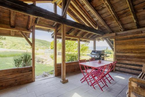 une table rouge sur un porche grillagé avec un gril dans l'établissement Le Chalet trésor caché au cœur de la nature, à Présilly