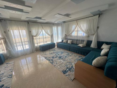 a living room with a blue couch and windows at Villa MANSOURA in Driouch