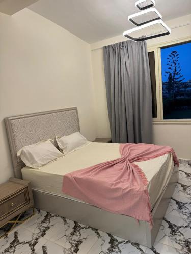 a bedroom with a bed with pink sheets and a window at قصر الأحلام فيلا أول سكن بمسبح خاص ومساحة 2000 متر in El Alamein