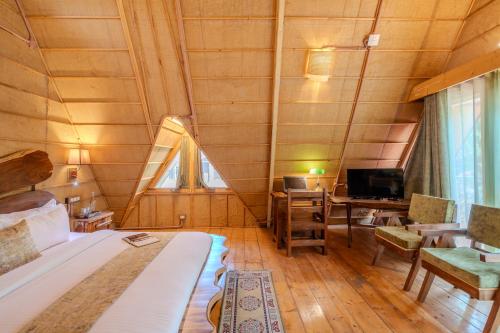 a bedroom with a bed and a desk with a computer at SaffronStays The Divine Hima in Dharamshala