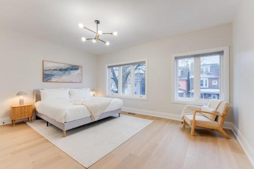een witte slaapkamer met een bed en een stoel bij 3BR Home in Trinity Bellwoods - 2 Parking Spots in Toronto