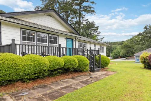 a white house with a black fence and bushes at 5BR with Game Room & Huge Backyard in Lawrenceville