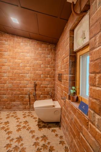 a bathroom with a toilet in a brick wall at SaffronStays The Divine Hima in Dharamshala