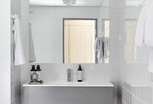 a white bathroom with a sink and a mirror at Stay North Matri House Edla in Mathildedal