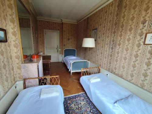 a room with two beds in a room with wallpaper at Château Champêtre 8 chambres, parc 18 ha, 4 étangs in Fontenoy