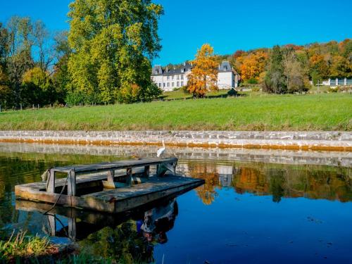 a boat in the water with a house in the background at Château Champêtre 8 chambres, parc 18 ha, 4 étangs in Fontenoy