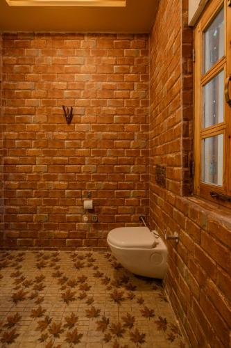 a bathroom with a toilet in a brick wall at SaffronStays The Divine Hima in Dharamshala