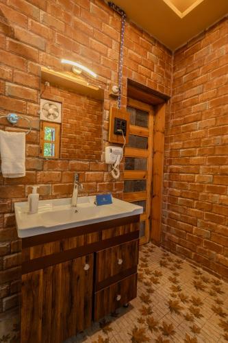 a bathroom with a sink and a brick wall at SaffronStays The Divine Hima in Dharamshala
