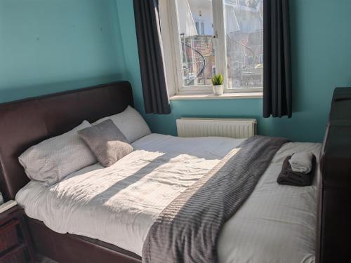 a bed in a blue room with a window at Double Rooms near Bournemouth Hospital ensuite or shared bathroom options in Bournemouth