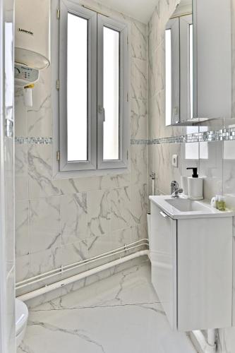 une salle de bain blanche avec un lavabo et un miroir dans l'établissement Magnifique 2 pieces aux portes de Paris- II, à Gagny