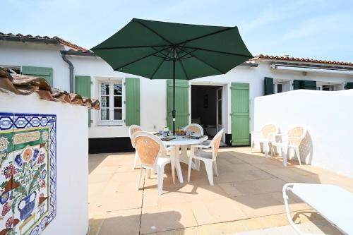 d'une terrasse avec une table et un parasol vert. dans l'établissement 080 Domaine 80 Courtyard, pool, tennis, à La Couarde-sur-Mer