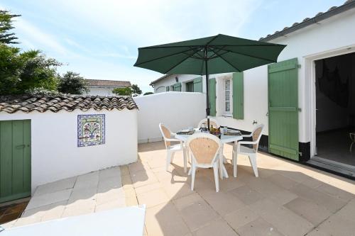 un patio avec une table et un parasol vert dans l'établissement 080 Domaine 80 Courtyard, pool, tennis, à La Couarde-sur-Mer