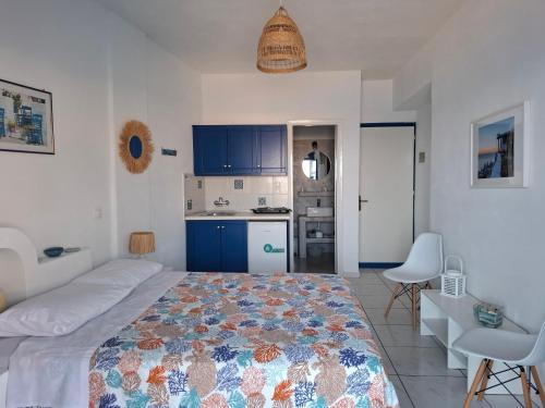 a bedroom with a bed and a kitchen with blue cabinets at Vrahos Rooms - Studios in Alopronia
