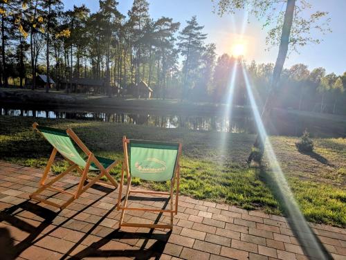 two lawn chairs sitting next to a lake at Leśna Przystań Nowy Kobrzyniec in Kobrzyniec Nowy