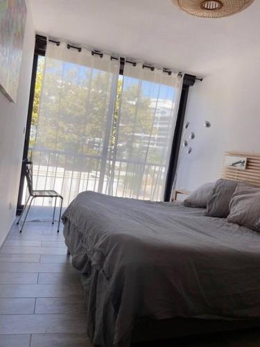 une chambre avec un lit et une grande fenêtre dans l'établissement Première ligne au Couchant Appartement t3 pour 6 personnes N112, à La Grande Motte