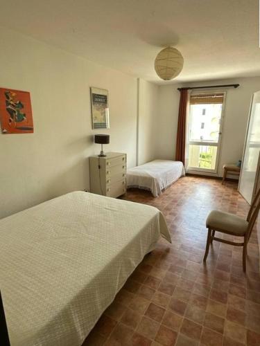 une chambre avec deux lits et une chaise et une fenêtre dans l'établissement Centre ville Appartement t2 pour 3 personnes N2 114, à La Grande Motte