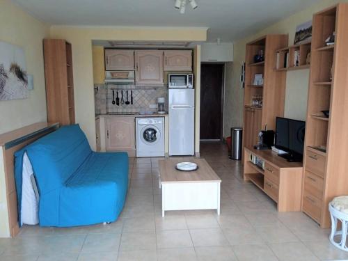 un salon avec un canapé bleu et une cuisine dans l'établissement Première ligne Plage Appartement studio pour 2 personnes N20, à La Grande Motte