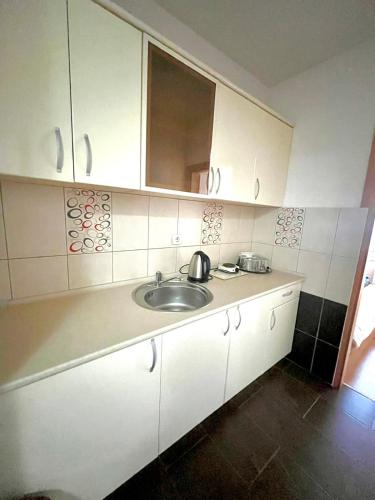 a white kitchen with a sink and a mirror at A&M Apartments in Ohrid