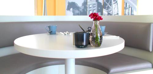 a white table with a vase and two cups on it at The Grey Design Hotel in Dortmund