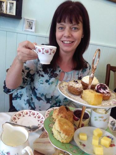 a woman sitting at a table with a cup of coffee at Ashfield House Failte Ireland Approved Bed and Breakfast in Cong