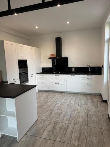 une cuisine avec des armoires blanches et un comptoir noir dans l'établissement Le Clos Monial sleeps 8, à La Celle-sous-Gouzon