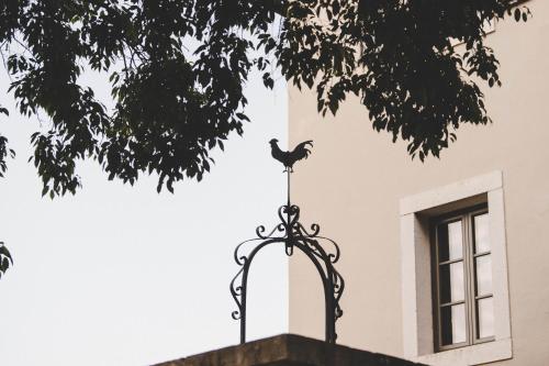 a bird on a weather vane in front of a building at San Tomasini Heritage Hotel & Wedding Venue in Višnjan