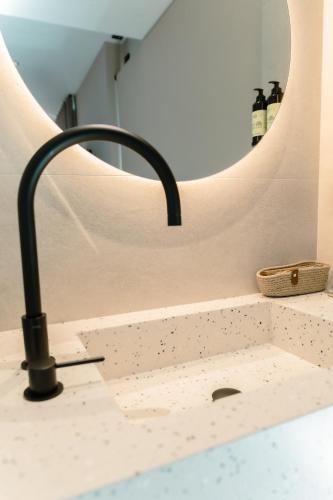 a bathroom sink with a faucet in front of a mirror at HOTEL RURAL FINCA LA DESA in Miajadas