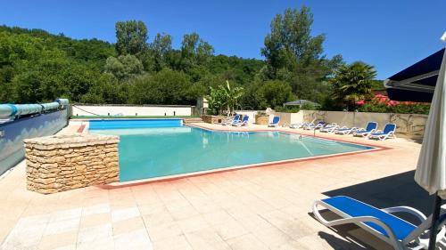 une piscine avec des chaises longues et une piscine dans l'établissement Lodge Holidays - Les Tailladis, à Marcillac-Saint-Quentin