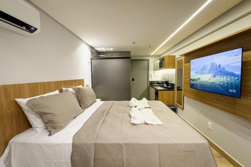 a bedroom with a large bed with a tv on the wall at Setai à beira-mar com rooftop incrível in João Pessoa