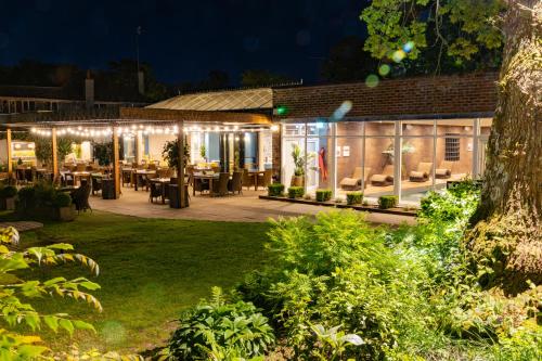 a restaurant with lights in a garden at night at Rooms at David Lloyd Wickwoods in Albourne