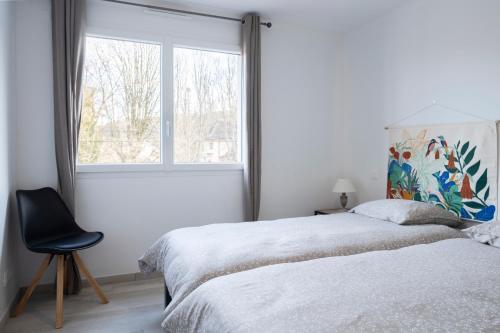 a bedroom with two beds and a chair next to a window at La route verte in Docelles