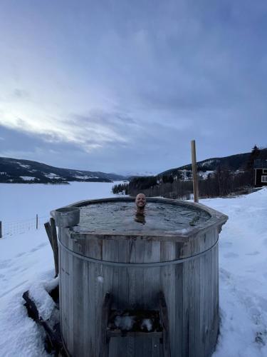 a wooden barrel in the snow next to a body of water at Experience Jotunheimen from Vevstogo - sauna with a view and eco living in an old school building in Løken