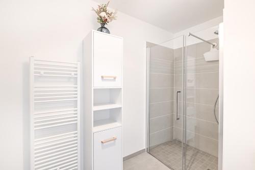 La salle de bains est pourvue d'armoires blanches et d'une douche. dans l'établissement Le Coquillage - Joli T3 avec grand balcon, à Courseulles-sur-Mer