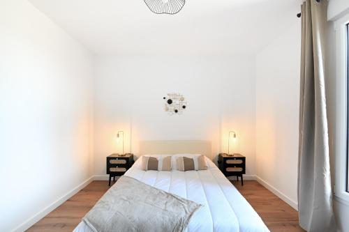 une chambre blanche avec un lit et deux tables de nuit dans l'établissement Le Coquillage - Joli T3 avec grand balcon, à Courseulles-sur-Mer