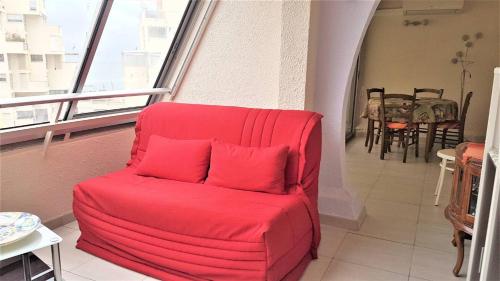 Cette chambre dispose d'un balcon et d'une chaise rouge. dans l'établissement Cœur de ville Appartement t2 pour 4 personnes N22, à La Grande Motte