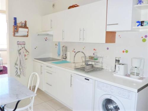 une cuisine blanche avec une machine à laver à l'intérieur dans l'établissement Cœur de ville Appartement t2 pour 4 personnes N22, à La Grande Motte