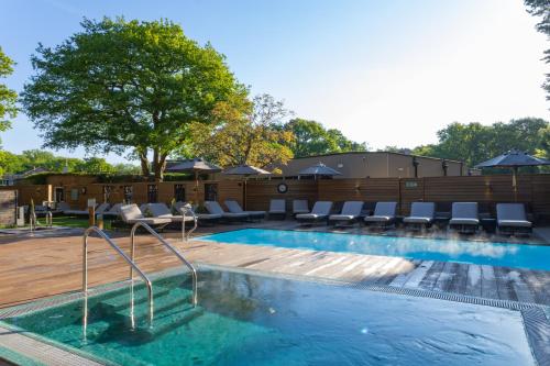 a swimming pool with lounge chairs at Rooms at David Lloyd Wickwoods in Albourne