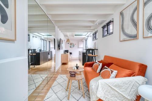 un salon avec un canapé orange et une table dans l'établissement Superbe Loft lumineux Paris Alesia- II, à Paris