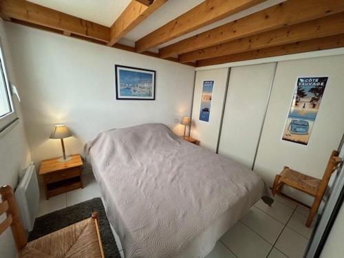 une chambre avec un lit dans une pièce avec des plafonds en bois dans l'établissement Appartement à Royan, proche plage, 2 chambres et balcon - FR-1-494-75, à Royan