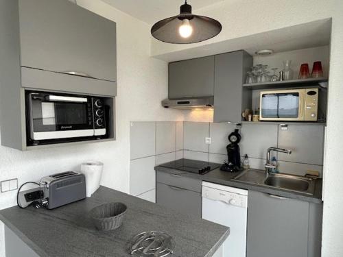 une cuisine avec un comptoir avec un évier et un micro-ondes dans l'établissement Appartement à Royan, proche plage, 2 chambres et balcon - FR-1-494-75, à Royan