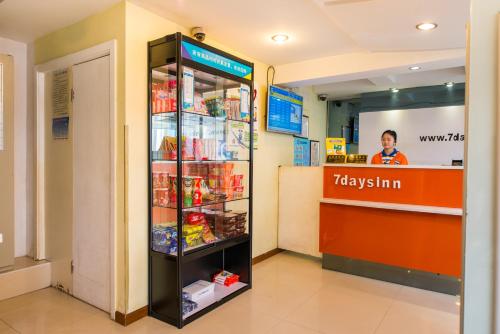 a drink cooler in a grocery store with a woman behind a counter at 7Days Inn Changshou Road Subway station in Shanghai