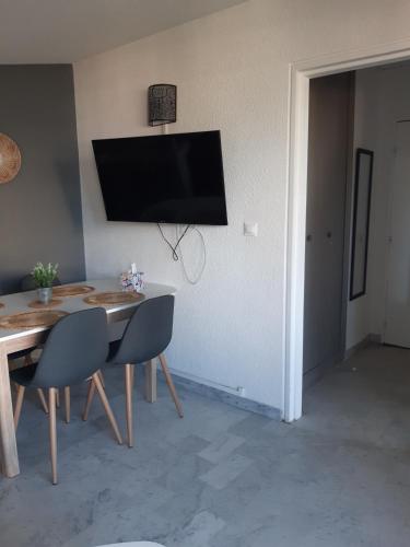 une salle à manger avec une table et une télévision au mur dans l'établissement Proche Port Appartement t2 pour 4 personnes N1 39, à La Grande Motte