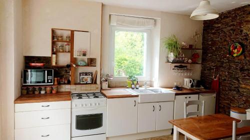 une cuisine avec des appareils blancs, une table et une fenêtre dans l'établissement Pierre et rivière - Une terrasse en ville, à Nantes