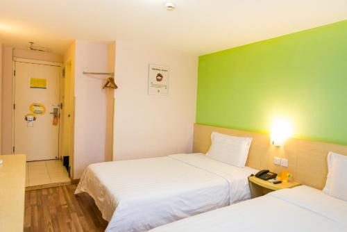a room with two beds and a green wall at 7Days Inn Changshou Road Subway station in Shanghai