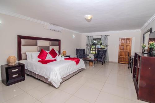 a bedroom with a large bed with red pillows at ASANTE MOUNTAIN LODGE in Hazyview