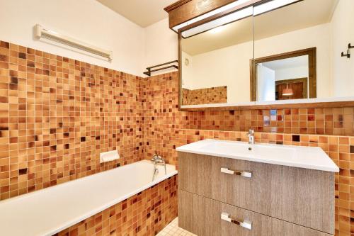une salle de bain avec un lavabo, une baignoire et un miroir dans l'établissement Appartement Mont d Arbois Megeve sur les pistes de ski, à Megève