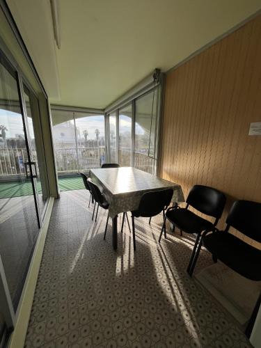 une table et des chaises dans une pièce avec des fenêtres dans l'établissement Quartier Point Zéro appartement studio pour 5 personnes N3, à La Grande Motte